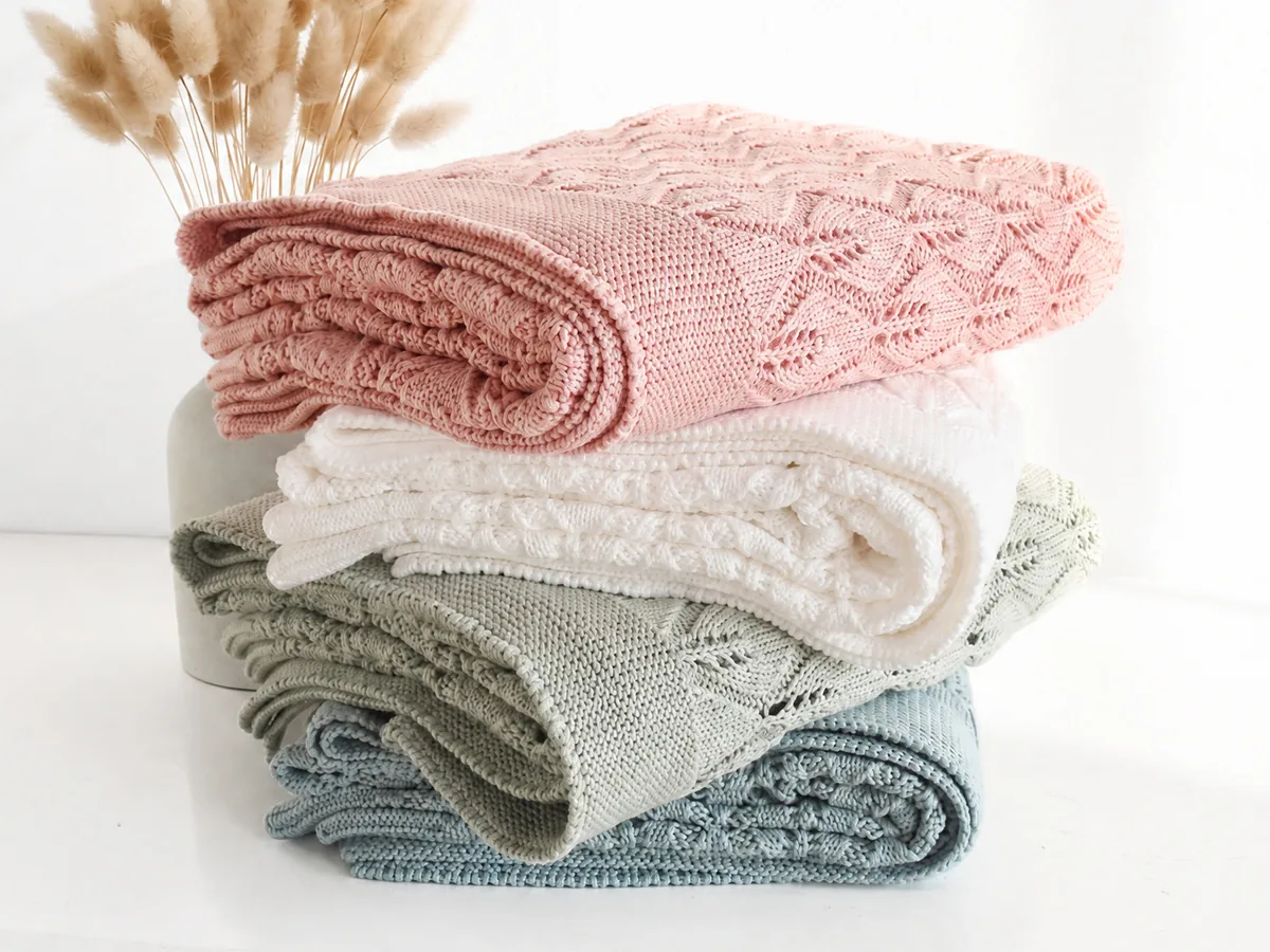 Folded knitted baby blankets in soft neutral colors