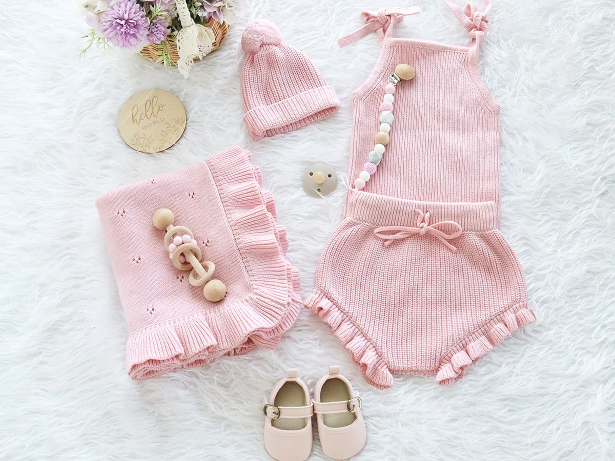 Pink knitted baby clothing set with romper, blanket and hat